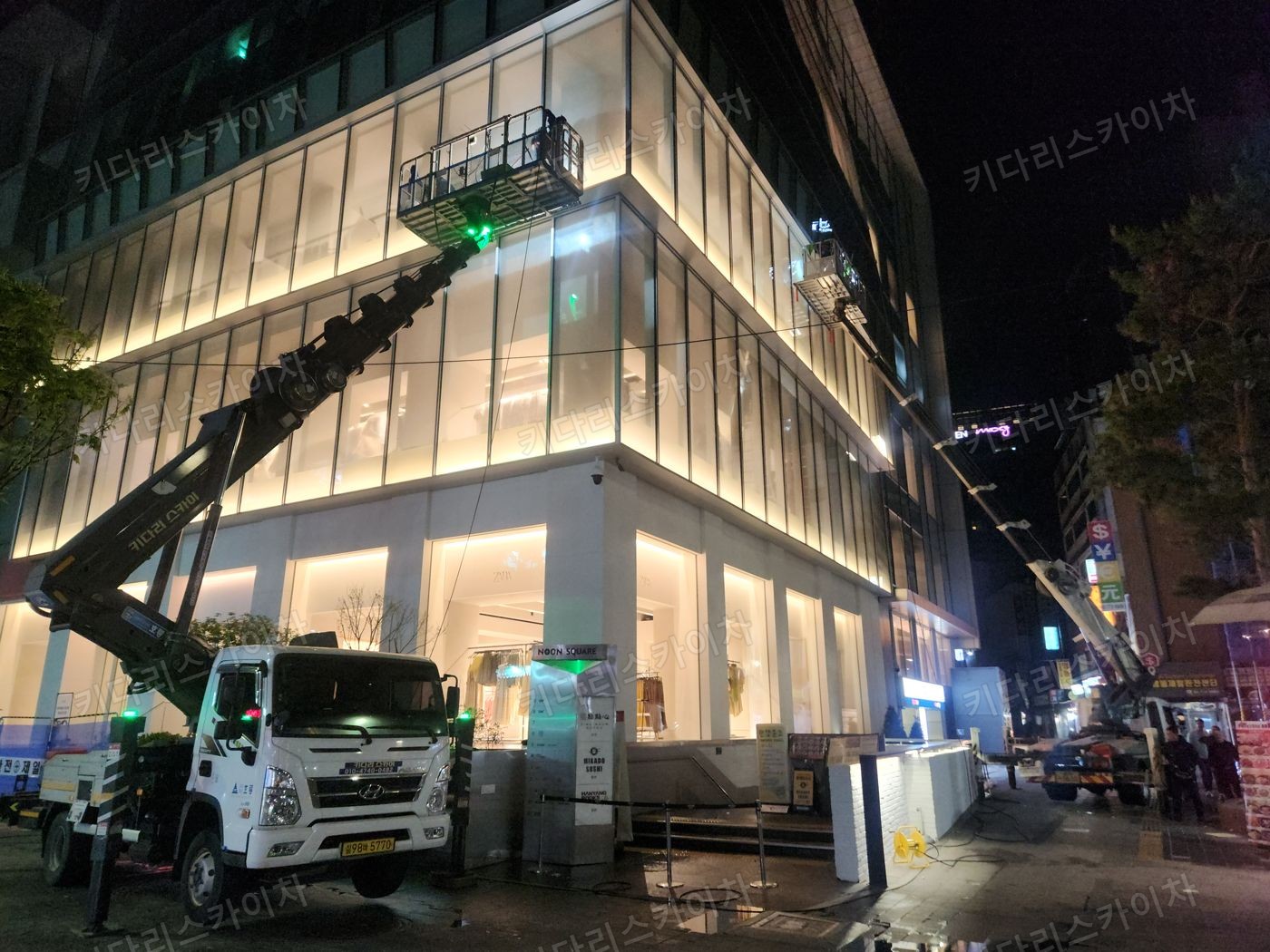 조명이 켜진 상가 외벽 앞 야간 장비 배치