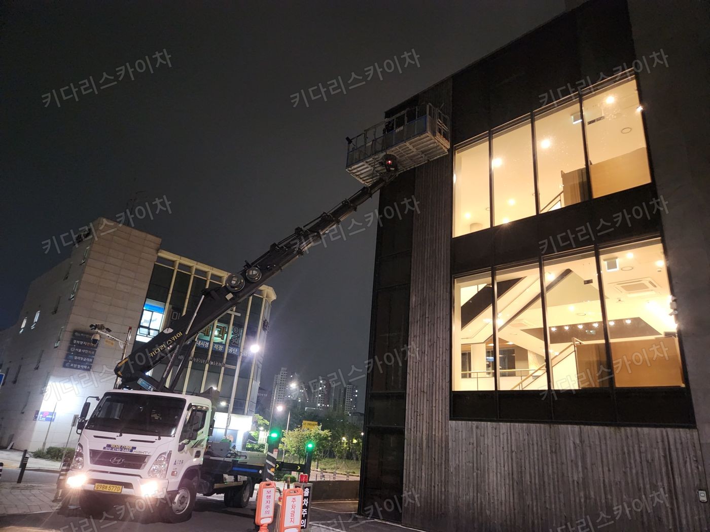 조명이 켜진 상가 외벽 앞 야간 장비 배치